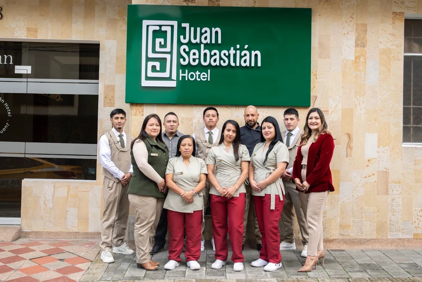 En gruppe hotelmedarbejdere foran skiltet for Juan Sebastián Hotel.