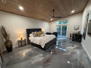 Een moderne slaapkamer met een groot bed, een plafondventilator en uitzicht op de omgeving via een schuifdeur.