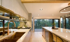 Una cocina moderna con una isla central, electrodomésticos de acero inoxidable y un amplio ventanal con vistas al exterior.