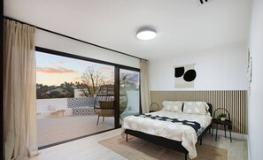 Un dormitorio moderno con una cama grande, vistas al exterior y una decoración minimalista.
