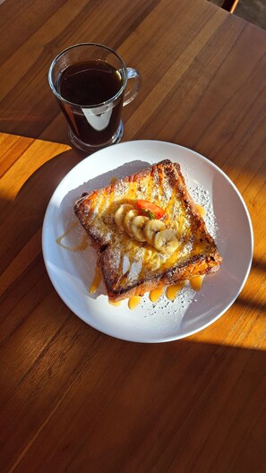 A plate with a grilled sandwich and a cup of coffee on a wooden table.