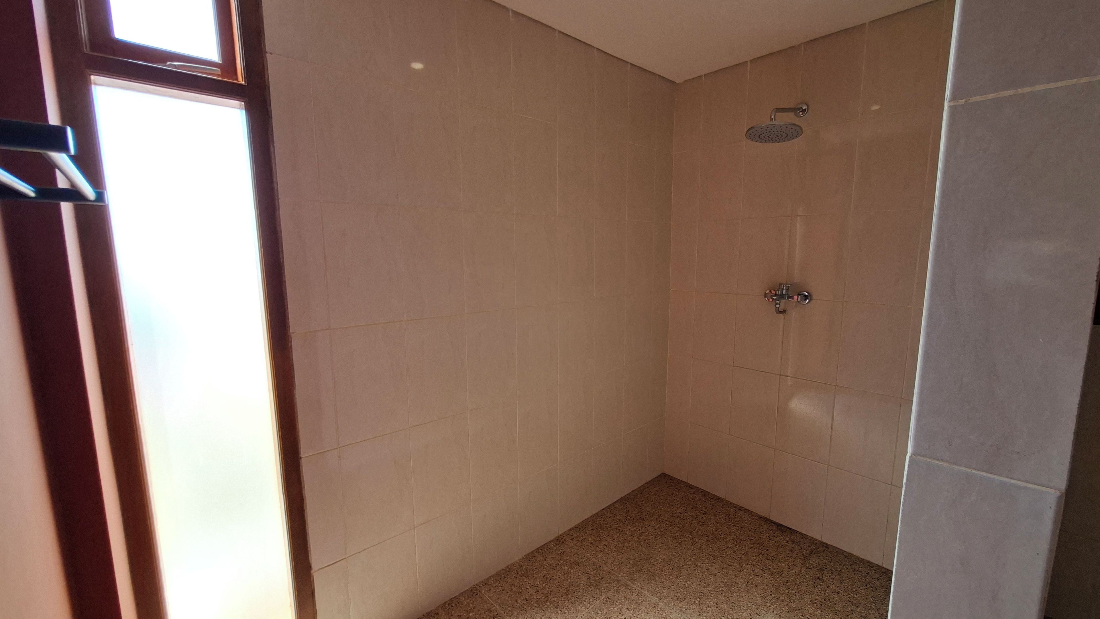 Un baño pequeño y revestido con azulejos, con cabezal de ducha y grifo.