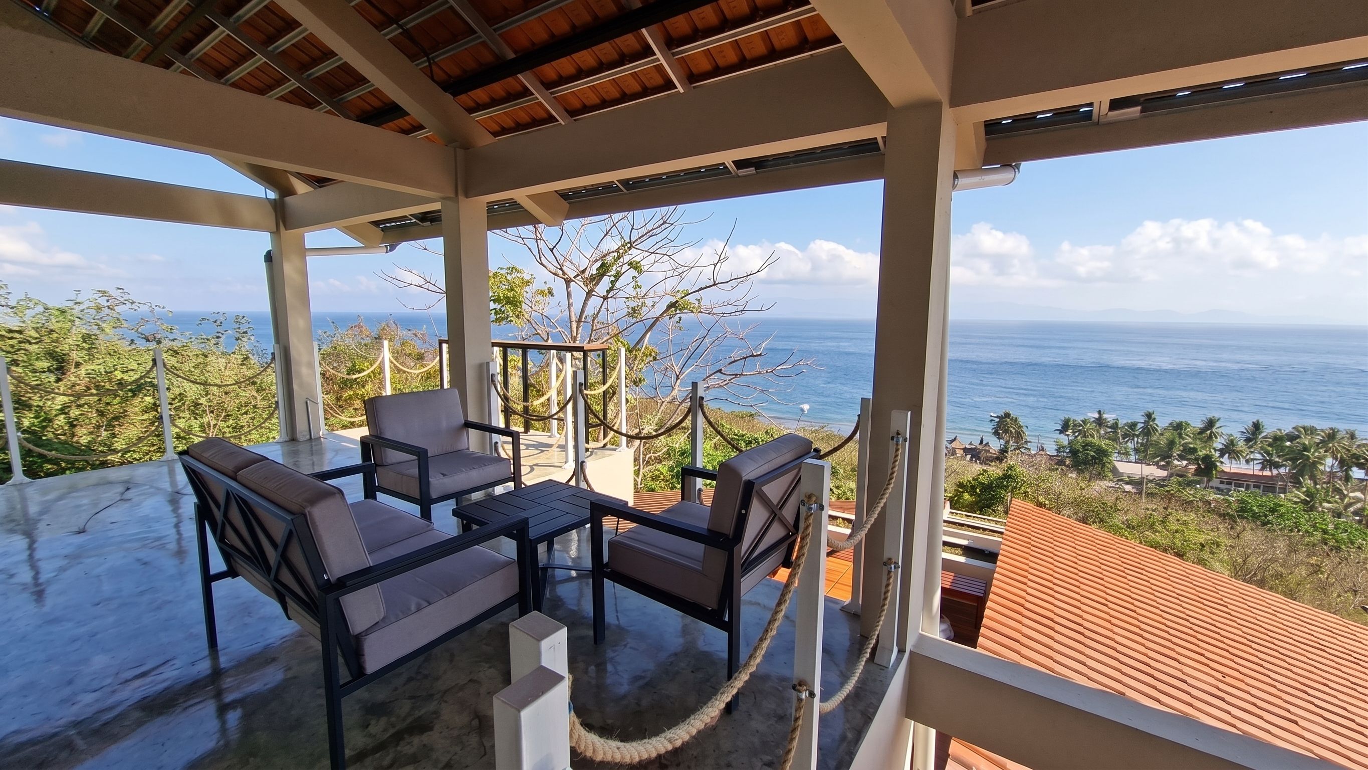 Uma área de estar coberta ao ar livre com vista para o oceano.