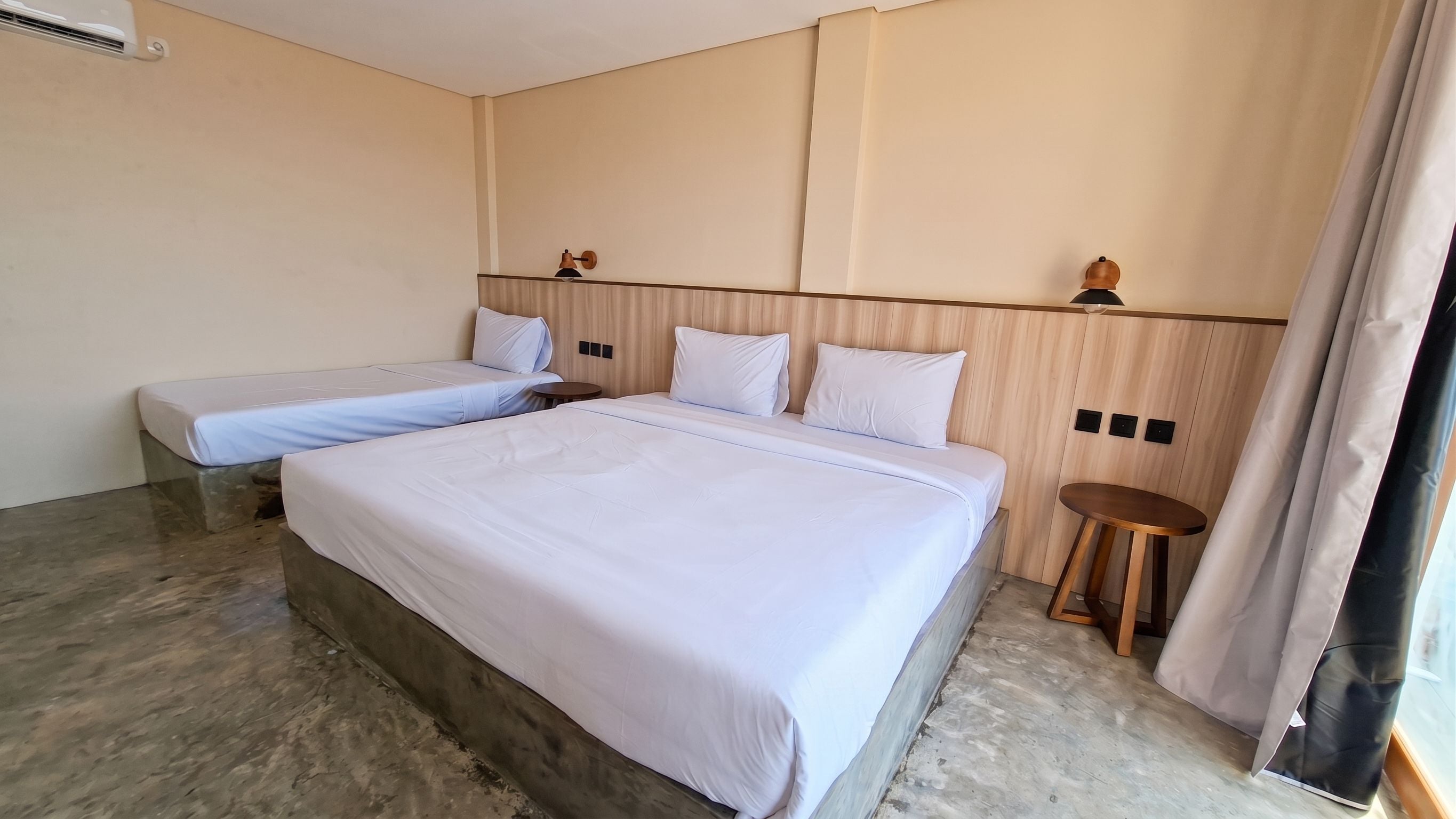 A hotel room with two beds, a small round table, and a wooden headboard.