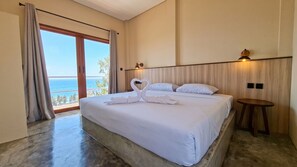 A hotel room with a large bed, a view of the ocean, and a wooden headboard. - Wonderloft Hostel Nusa Penida (Klungkung)