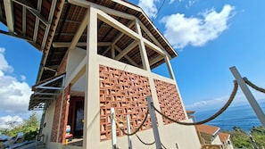 A building with a unique geometric facade, a visible entrance, and a view of the ocean. - Wonderloft Hostel Nusa Penida (Penida Island)
