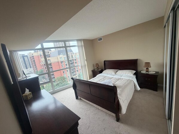 A bedroom with a large window, a bed, a dresser, and two bedside tables with lamps. - Cozy 2Bed 2Bath-CN Tower view- Yonge & Sheppard (Toronto)