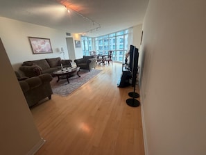 A spacious living room with hardwood flooring, a sofa set, a coffee table, and a television. - Cozy 2Bed 2Bath-CN Tower view- Yonge & Sheppard (Toronto)