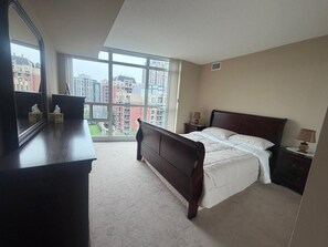 A bedroom with a large window, a bed, a dresser, and a nightstand. - Cozy 2Bed 2Bath-CN Tower view- Yonge & Sheppard (Toronto)
