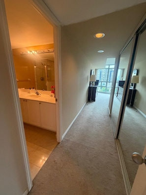 A hallway leading to a bathroom with a shower, a sink, and a mirror. - Cozy 2Bed 2Bath-CN Tower view- Yonge & Sheppard (Toronto)