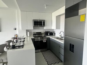 A modern kitchen with stainless steel appliances, a microwave, and a refrigerator. - Oceanview Studio in Ocho Rios with Pool (Ocho rios)