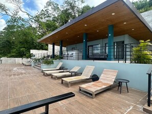 An outdoor lounge area with wooden loungers and a covered seating area. - Oceanview Studio in Ocho Rios with Pool (Ocho rios)