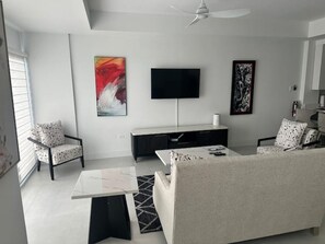 A modern living room with a sofa, armchairs, a coffee table, a flat-screen TV mounted on the wall, and artwork. - Oceanview Studio in Ocho Rios with Pool (Ocho rios)