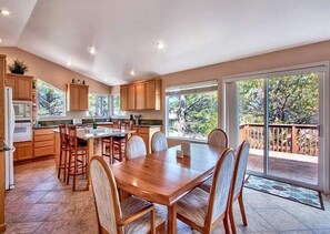 A spacious kitchen with a dining area, large windows, and a view of the outdoors. - Keys Lagoon Retreat (South Lake Tahoe)