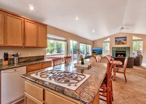 A spacious kitchen with a central island, dining area with chairs, and a fireplace. - Keys Lagoon Retreat (South Lake Tahoe)