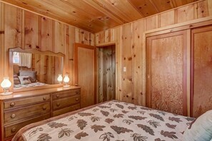 Ein Schlafzimmer mit Holzwänden, einem Bett, einem Schminktisch und einem Spiegel.