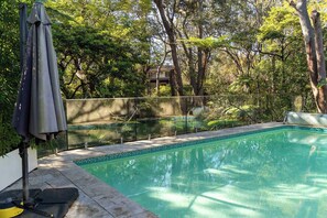 A swimming pool with a tiled edge, surrounded by a fence and trees. - Elegant Lane Cove Sanctuary (Lane Cove)