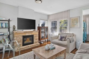 Una sala de estar con chimenea, televisor, sofá y una mesa de centro.