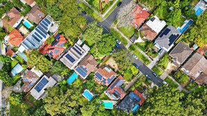 Vista aérea de una zona residencial con casas, paneles solares y zonas verdes.