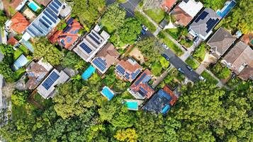 An aerial view of a residential area with houses, solar panels, and green spaces.