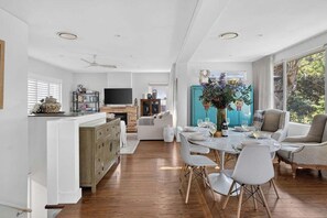 A modern kitchen with a dining area, wooden flooring, and a large window providing natural light. - Elegant Lane Cove Sanctuary (Lane Cove)