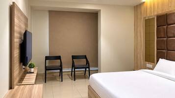 Un dormitorio moderno con una cama, dos sillas, un televisor y un ventilador de techo.