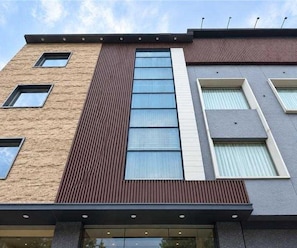 Un edificio de varios pisos con fachadas de ladrillo y paneles, ventanas grandes y techo plano.