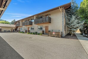 A multi-story building with a flat roof, balconies, and a gravel driveway. - Downtown Leavenworth 2BR/2BA condo with fireplace, deck, parking. (Leavenworth)