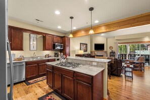A modern kitchen with wooden cabinets, a central island, stainless steel appliances, and pendant lighting. - Downtown Leavenworth 2BR/2BA condo with fireplace, deck, parking. (Leavenworth)