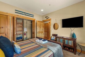 A bedroom with a bed, a TV, a wooden wardrobe, and a small table. - Downtown Leavenworth 2BR/2BA condo with fireplace, deck, parking. (Leavenworth)