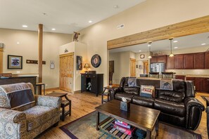 A spacious living room with a leather sofa, patterned armchair, and a coffee table with board games. - Downtown Leavenworth 2BR/2BA condo with fireplace, deck, parking. (Leavenworth)