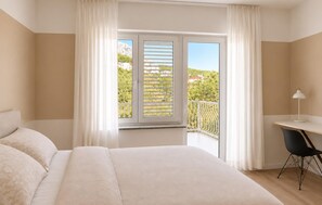 A bedroom with a bed, a desk, and a chair. There is a window with blinds and a view of greenery outside. - 3 bedroom amazing apartment in Jesenice (Jesenice)