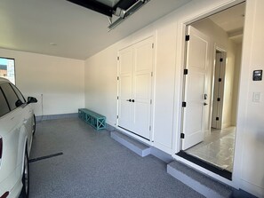A clean, modern interior with a car parked in the foreground, a set of double doors, and a small step leading to a door. - Luxury Skyridge home - sleeps 12 - large game room (Daniel)