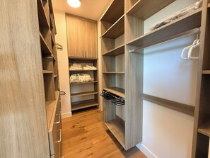 Ein begehbarer Kleiderschrank mit Holzböden, einer Kleiderstange und einer spiegelnden Schranktür.