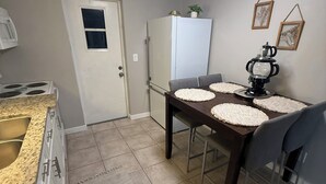 Una cocina con estufa, refrigerador y mesa de comedor con individuales.