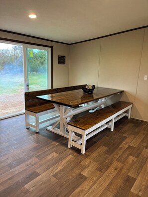 Ein Esstisch mit Bänken in einem Raum mit Holzboden und einem großen Fenster.