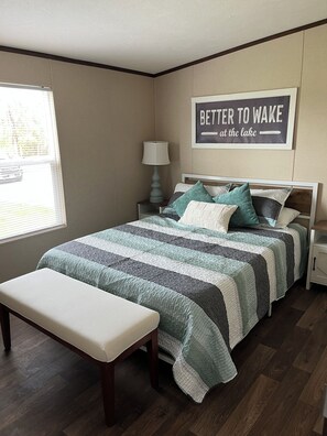 A bedroom with a bed, bench, nightstands, a lamp, and a motivational quote on the wall. - 5-bdr 3 bath fully furnished house in Burnside Ky minutes from Lake Cumberland (Burnside)