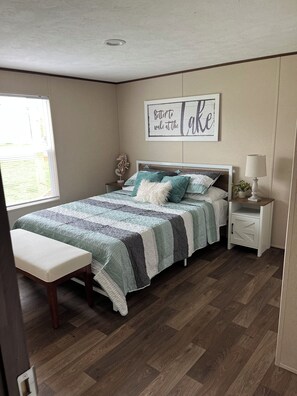 A bedroom with a bed, bedside table, lamp, bench, and a wall sign. - 5-bdr 3 bath fully furnished house in Burnside Ky minutes from Lake Cumberland (Burnside)