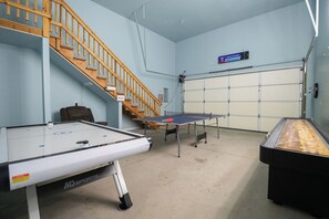 A ping pong table, a pool table, and a staircase in a room with light blue walls.