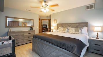 Une chambre à coucher comprenant un lit, des tables de chevet, une commode, un ventilateur de plafond et un miroir.