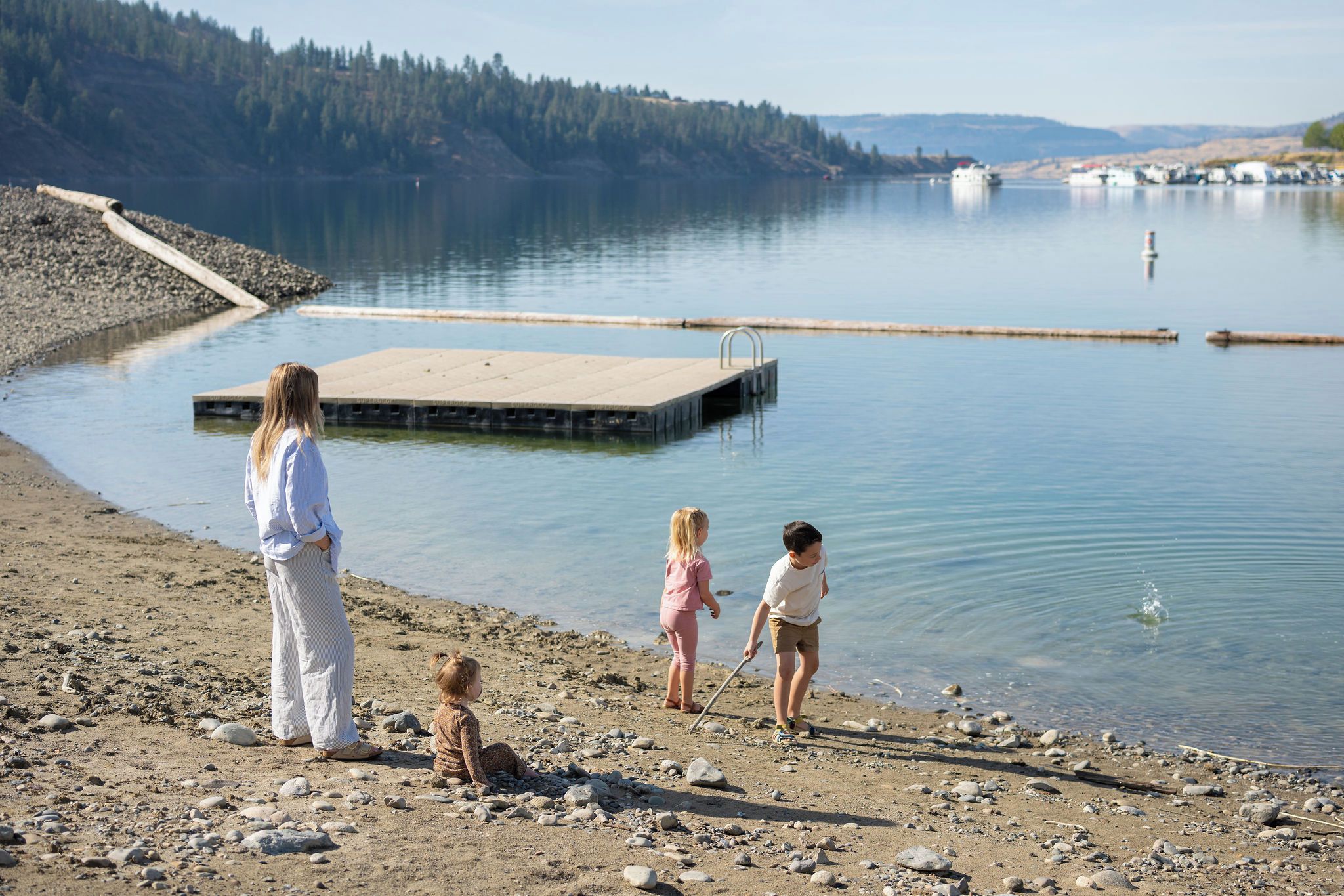 A family by a calm lake with a dock extending into the water.