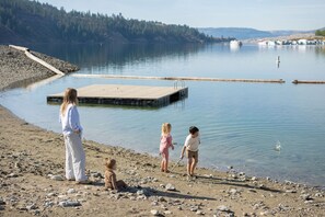 A family by a calm lake with a dock extending into the water.