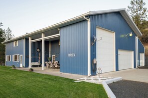A blue building with a garage, a covered patio with outdoor furniture, and a lawn.