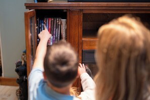 A person reaching into a wooden bookcase filled with books.