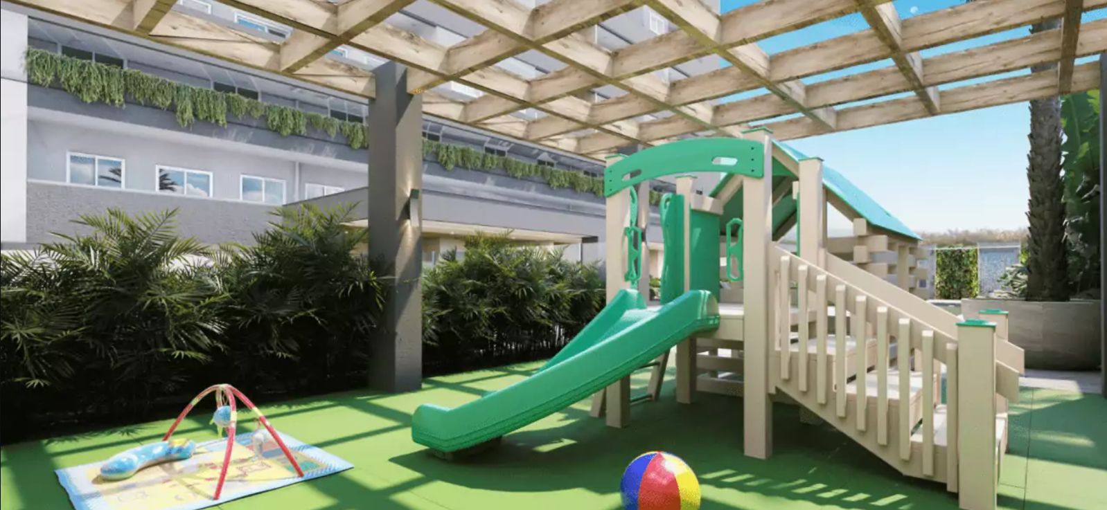 A playground with a slide and climbing structures, surrounded by greenery and a building with a green roof.