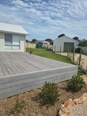 A residential property with a wooden deck, a garage, and a fenced backyard.