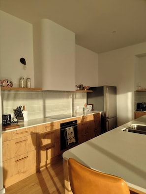 A modern kitchen with wooden cabinets, a stainless steel refrigerator, and a tiled backsplash.
