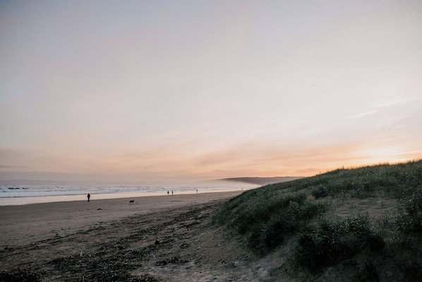 A beach with a dune and ocean in the background.