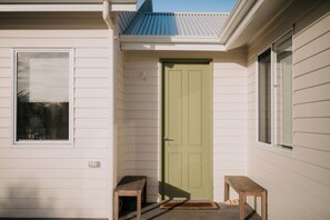 A house with a green door, two small wooden tables, and a window.