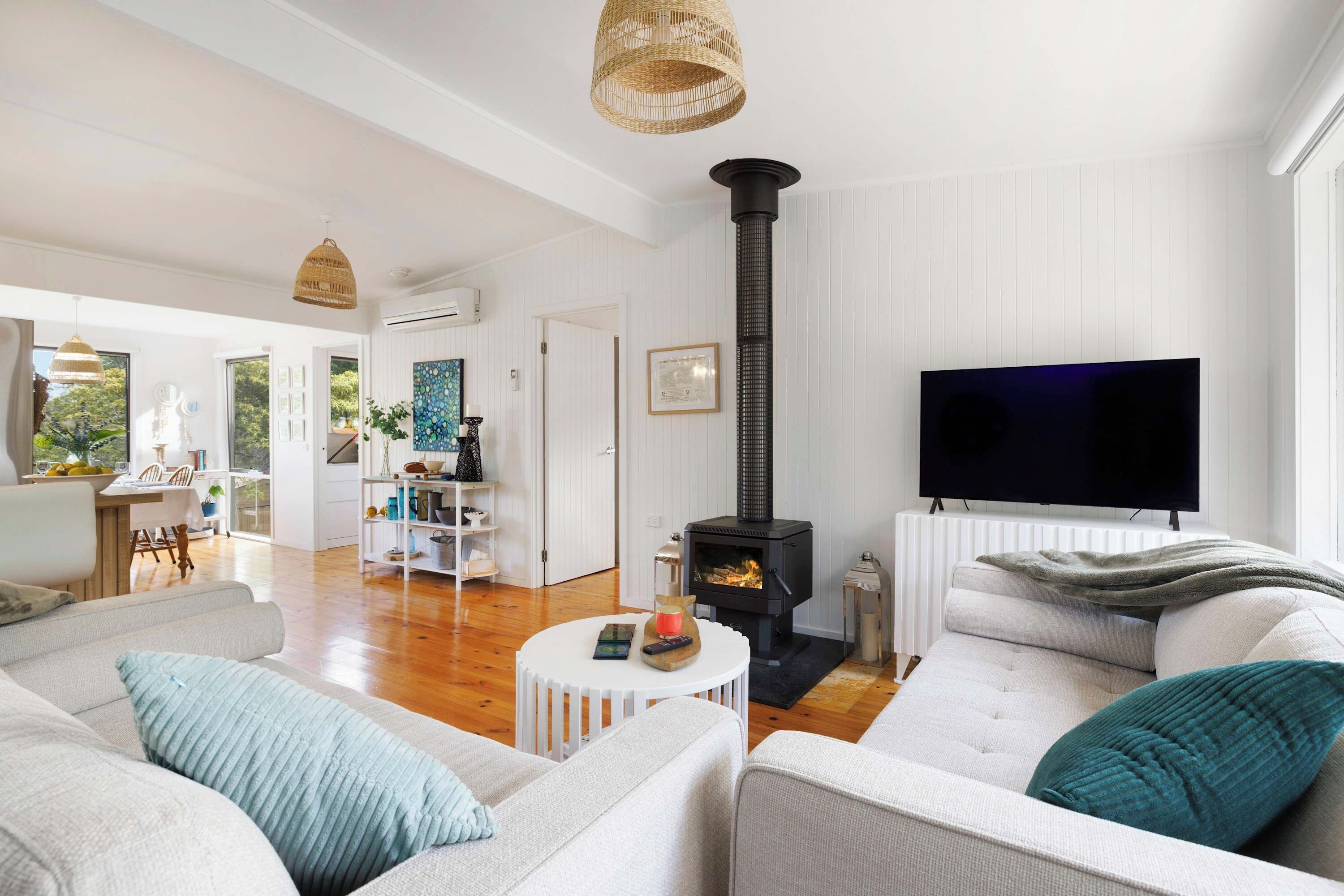 A modern living room with a black wood-burning stove, white sofas, and a flat-screen TV.